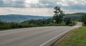 Long road with trees and mountains in the background.